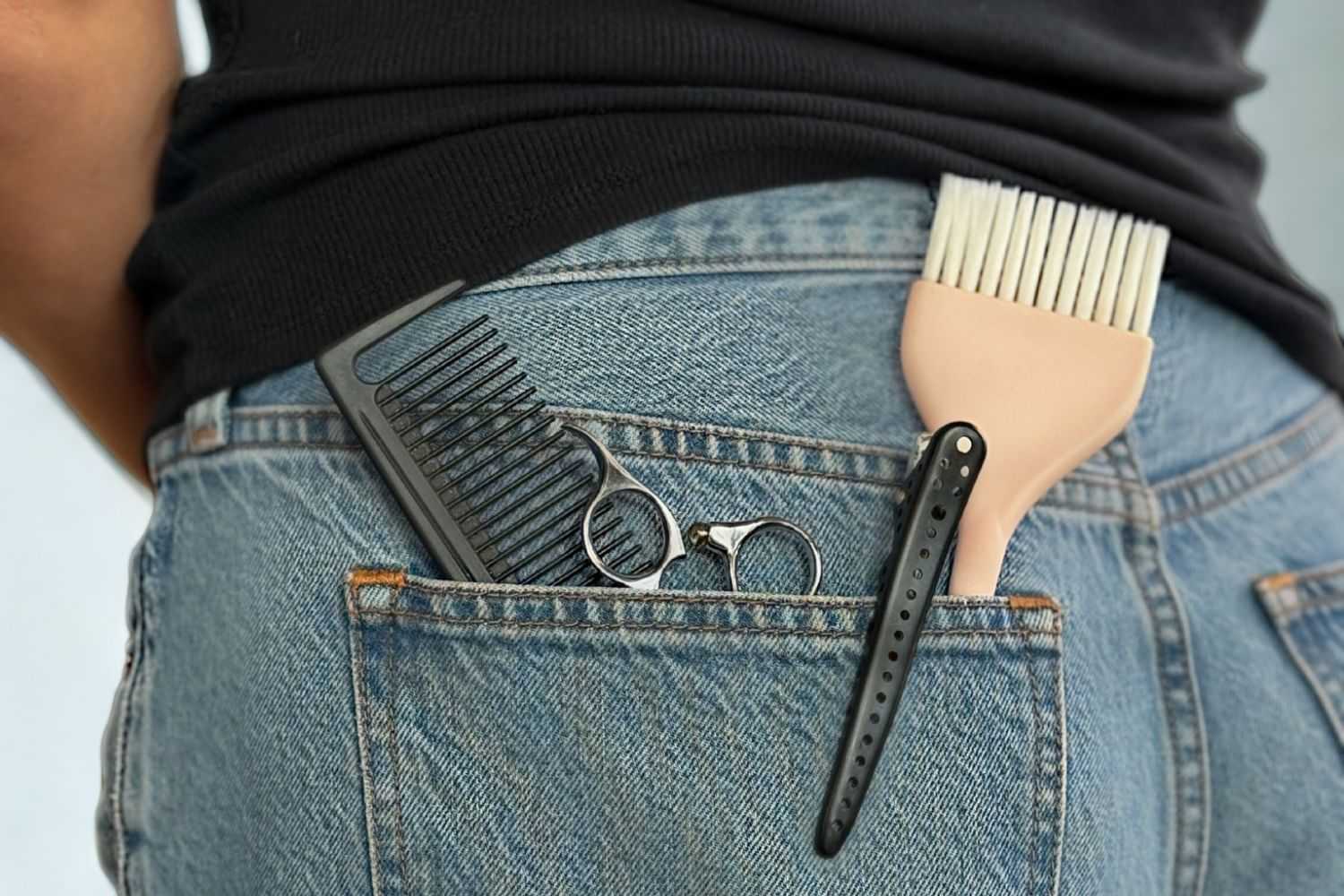 Combs and scissors in back pocket of blue jeans.